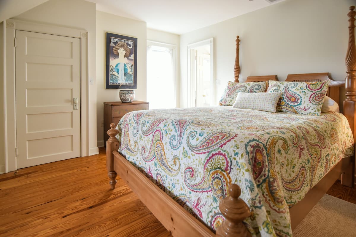 A bedroom with a wooden bed, a nightstand, a poster on the wall, and a door.