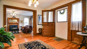 Un vaste salon doté d’un plancher en bois, d’un grand tapis, d’une cheminée et d’un coin repas avec une table et des chaises en bois.