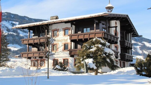 A multi-story building with balconies, surrounded by snow-covered trees and mountains. - Römerhof by Interhome (Fügen)