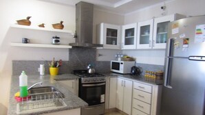 A kitchen with white cabinets, a stainless steel refrigerator, a microwave, an oven, and a sink. - Casa Nebel - Duplex (Concordia)
