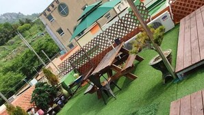 Un espacio al aire libre con césped artificial, mesas de madera y una terraza de madera.
