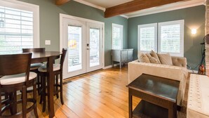 A dining area with a wooden table and chairs, a sofa, and a small table.