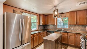 A modern kitchen with stainless steel appliances, wooden cabinets, and a tiled backsplash.