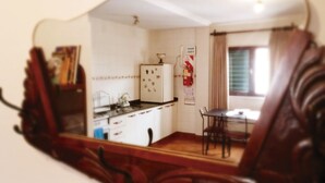 A compact kitchen with white cabinets, a refrigerator, and a small dining area with a table and chairs. - Buenos Aires 212 (Salta)