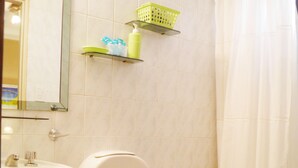A bathroom with a toilet, sink, and shower curtain. - Buenos Aires 212 (Salta)