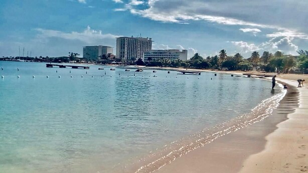 A beach with clear water, a sandy shore, and buildings in the background. - Luxe Beach Front Retreat (Ocho Rios)
