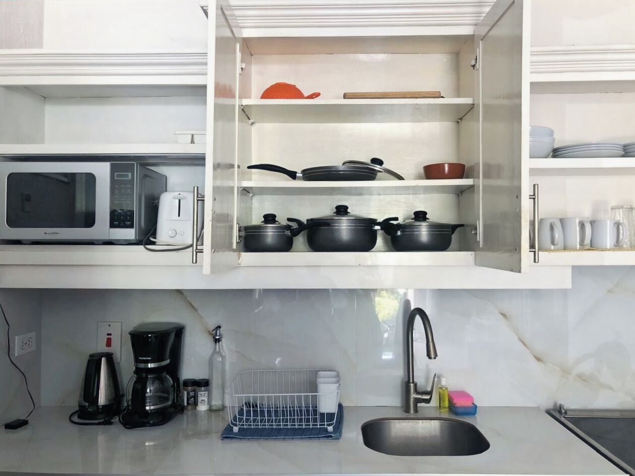 A kitchen with a microwave, coffee maker, and a dish rack.
