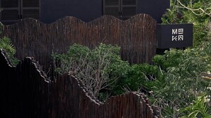 A modern building with a thatched roof, a bamboo fence, and lush greenery. - Maka Hotel Boutique (Tulum)