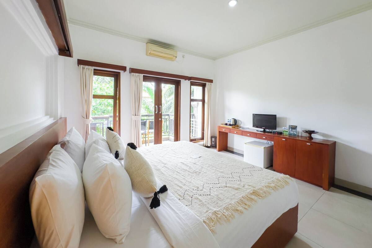 A bedroom with a bed, a desk, and a television.