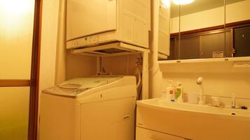 A compact laundry area with a washing machine, a dryer, and a sink with toiletries.