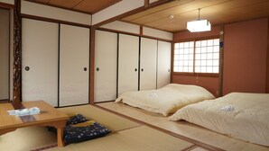 A traditional Japanese-style room with tatami flooring, two beds, a wooden table, and sliding doors. - Private House for Rabbit Island (Takehara)