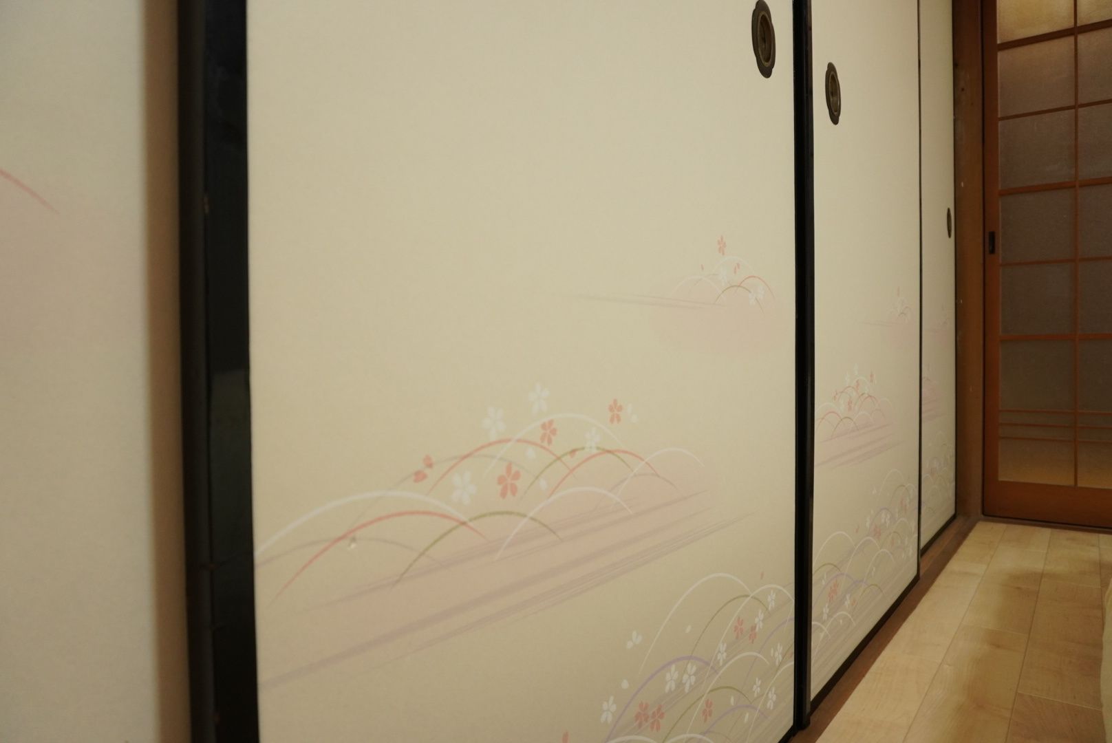 Un pasillo con una puerta corredera decorada con motivos florales.