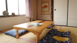 A traditional Japanese room with tatami flooring, a low wooden table, and a futon bed. - Private House for Rabbit Island (Takehara)