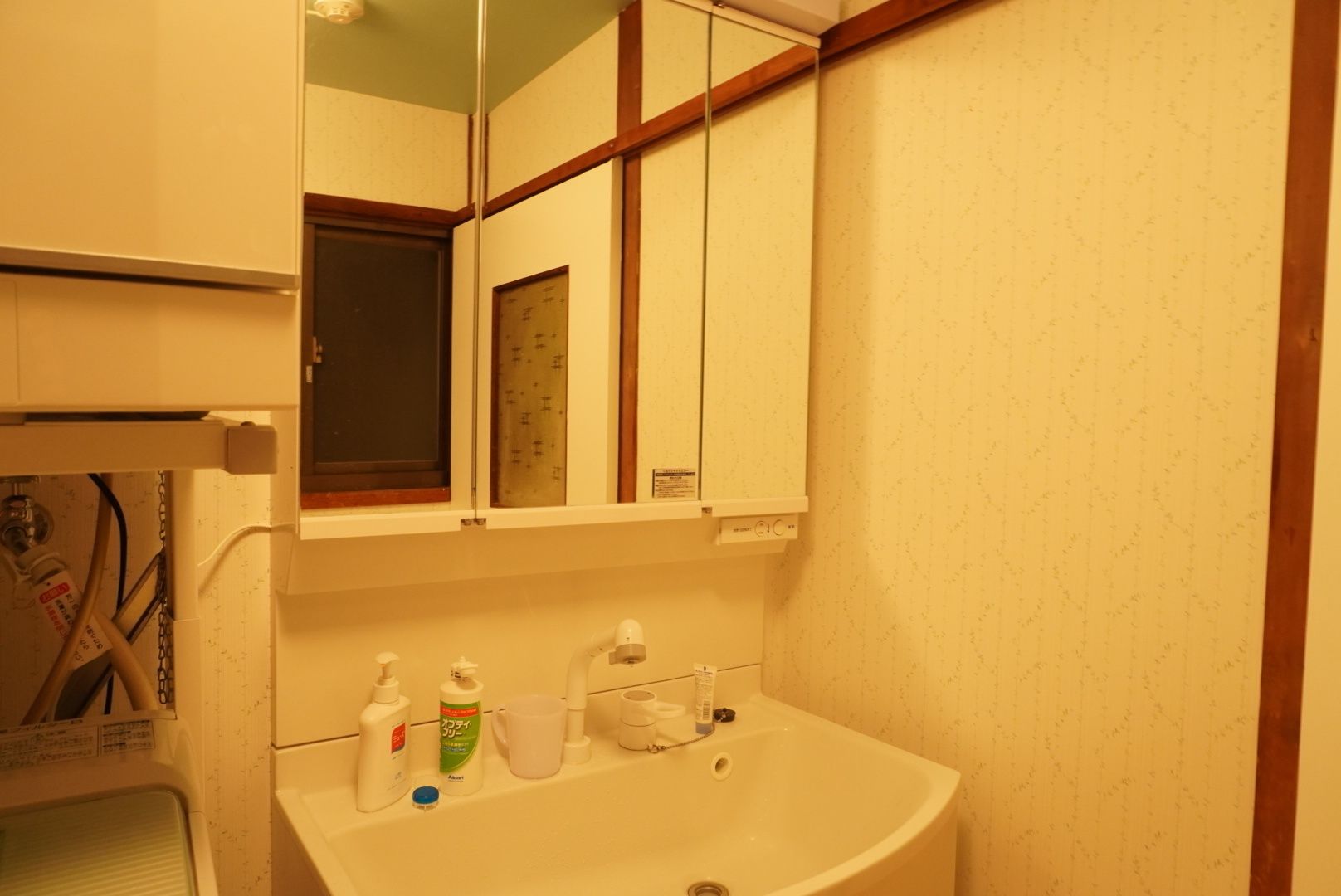 Een badkamer met een wit wastafelmeubel, spiegel en kast. Er staan toiletartikelen op de wastafel.