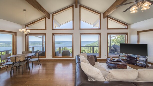 A spacious living room with a large window overlooking a scenic landscape, a comfortable seating area, and a flat-screen TV on a stand.
