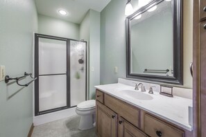 Une salle de bain équipée d’une douche, de toilettes et d’un meuble-lavabo avec un miroir et un évier.