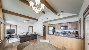 A spacious living area with a large wooden dining table, a sofa, and a TV.