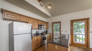 A kitchen with wooden cabinets, a stainless steel refrigerator, a microwave, and an oven.