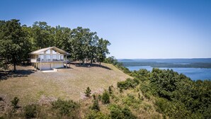 A cabin with a balcony overlooking a lake, surrounded by trees.