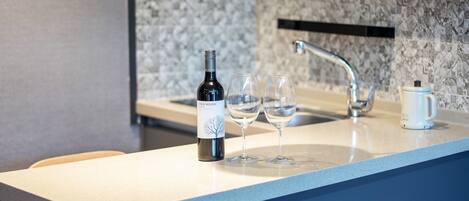 A kitchen counter with a wine bottle and two glasses.