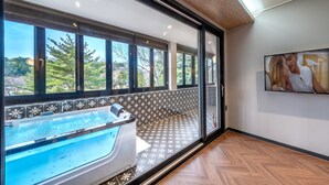 A modern bathroom with a large window, a bathtub, and a wooden floor.