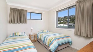 Un dormitorio con dos camas, una ventana y vistas a casas.