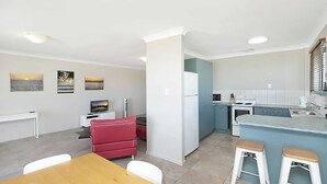 Una cocina moderna con comedor, que incluye un sofá rojo, una mesa de madera y una isla de cocina con taburetes.