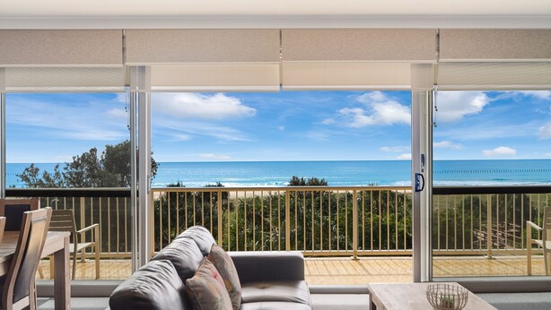 Un balcon avec vue sur l’océan, un canapé et une table.