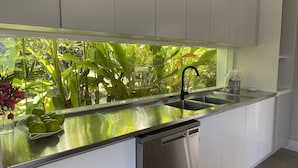 Une cuisine moderne dotée d’un plan de travail en acier inoxydable, d’un robinet noir et d’un lave-vaisselle.