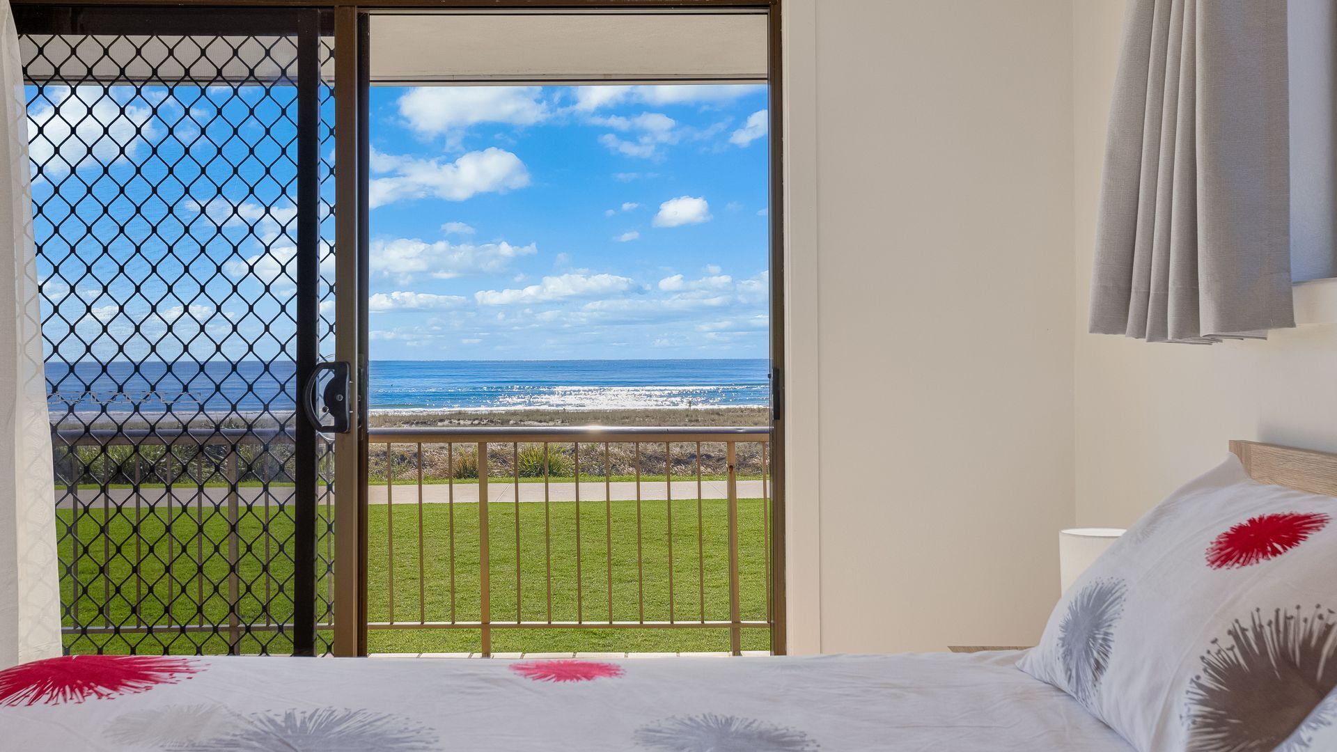 A bedroom with a view of the ocean through a sliding glass door.