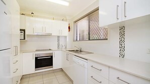 Una cocina moderna con armarios blancos, electrodomésticos de acero inoxidable y un salpicadero decorativo.