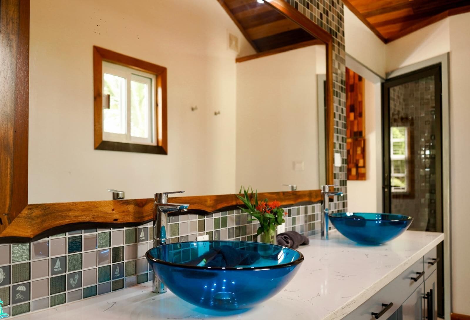 A bathroom with a white countertop, two sinks, and a large mirror.