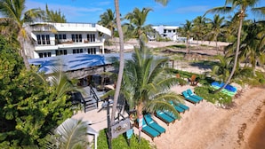 A resort with a two-story building, a covered outdoor seating area, and a beach with lounge chairs. - Mangata Villas (San Pedro)
