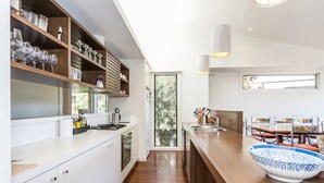 A modern kitchen with white cabinetry, a wooden countertop, and a large window. - Breaker Eight (Lorne)
