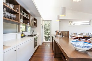Eine moderne Küche mit weißen Schränken, einer Holzarbeitsplatte und einem großen Fenster.