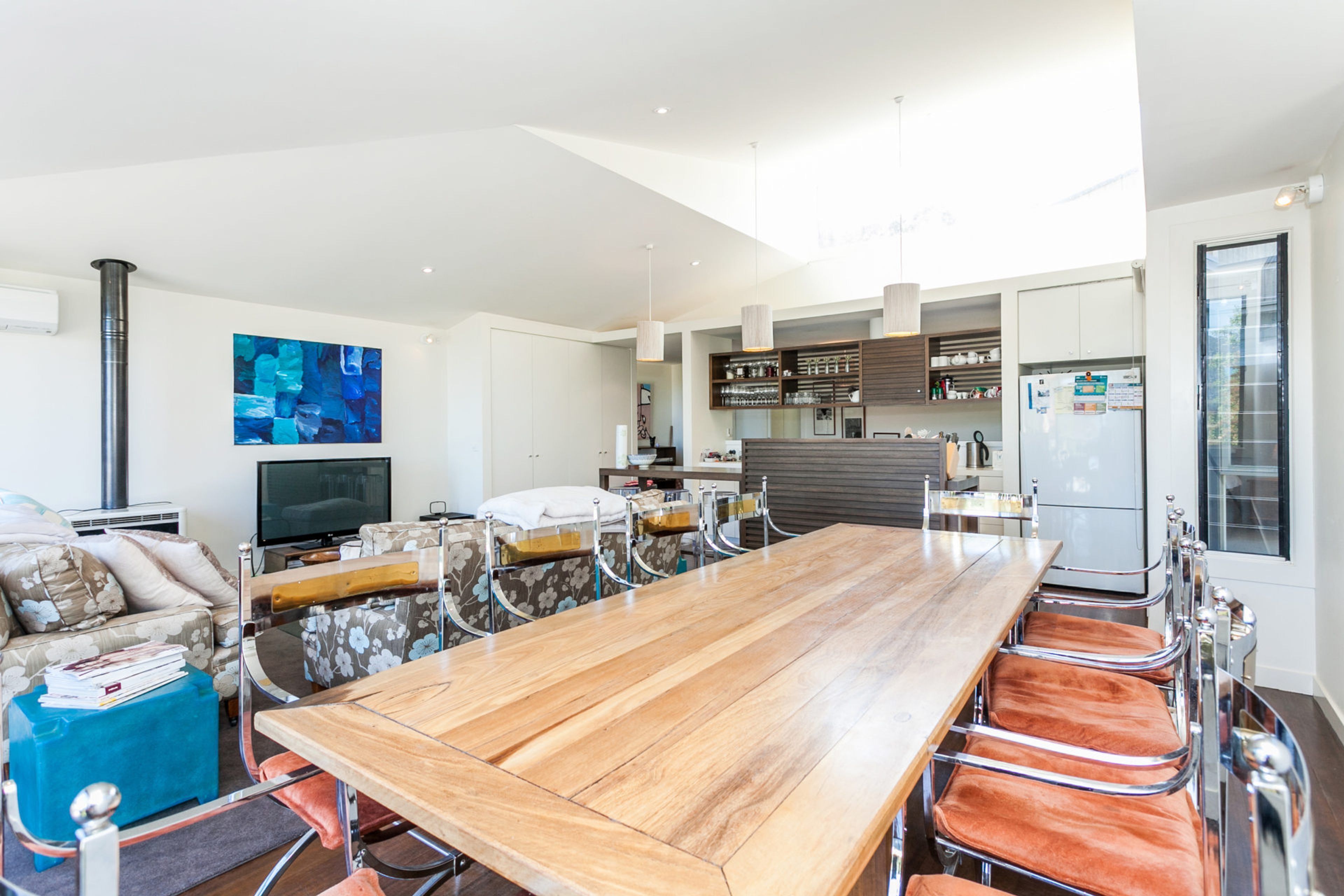 Une cuisine moderne avec une grande table en bois, des placards intégrés et un téléviseur à écran plat.