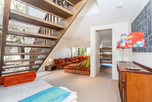 A spacious living area with a wooden staircase, a sectional sofa, and a flat-screen TV.