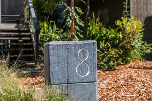 A wooden mailbox with the number 8, surrounded by greenery and mulch.