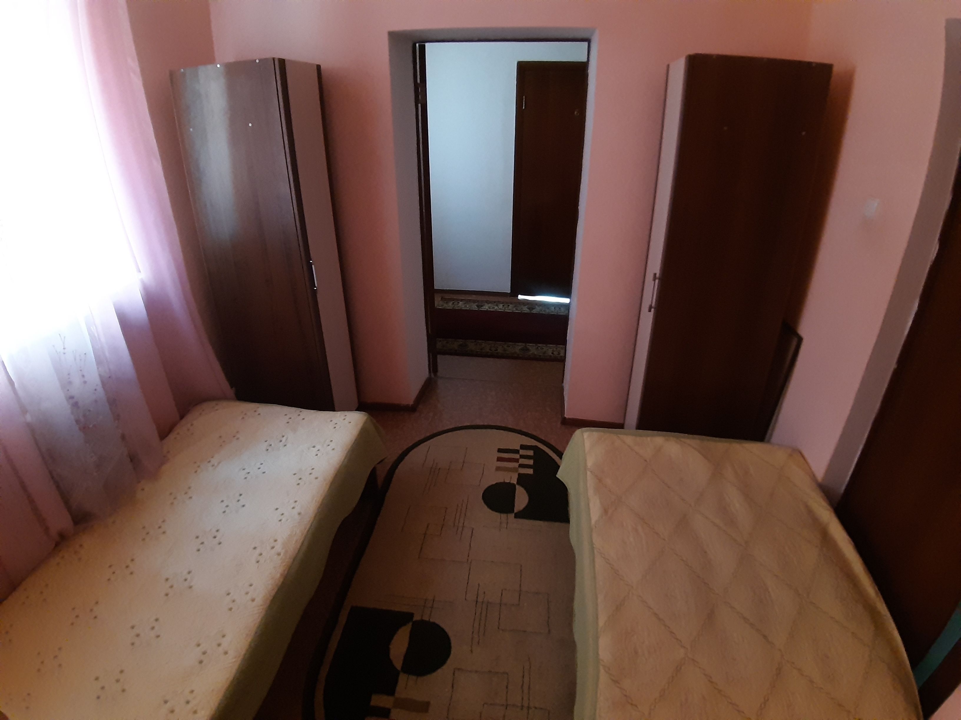 A room with two beds, a small table, and a door leading to another room.