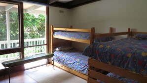 A room with a bunk bed, a bench, and a sliding glass door leading to an outdoor area.