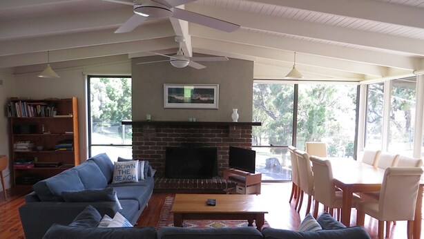 A living room with a fireplace, a sofa, a television, and a dining area with chairs.