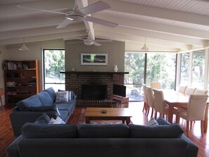 A living room with a fireplace, a sofa, a television, and a dining area with chairs.