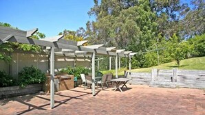 An outdoor patio with a pergola, seating area, and a brick floor.