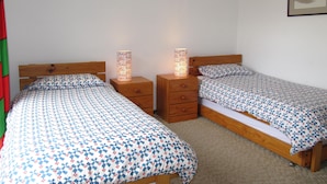 A bedroom with two single beds, wooden headboards, and bedside tables with lamps.