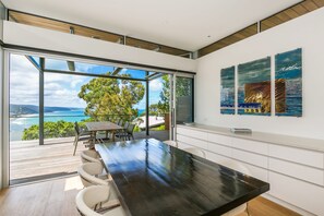 Una cocina moderna con una isla grande, un comedor con vista al océano y obras de arte en las paredes.