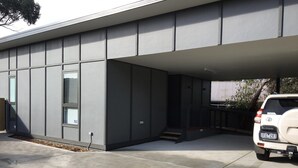 Un bâtiment moderne doté d’un toit plat, de grandes fenêtres et d’un espace de stationnement couvert.