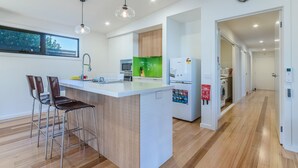 Une cuisine moderne dotée d’un îlot central, de tabourets de bar, d’un four à micro-ondes, d’un réfrigérateur et d’un lave-linge.