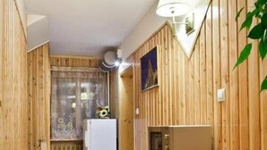 Un pasillo estrecho con paneles de madera, un refrigerador blanco, un microondas y un pequeño basurero.