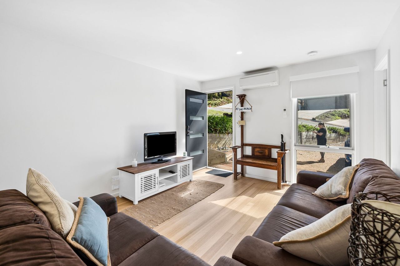 A modern living room with a flat-screen TV, a wooden coffee table, and a brown leather sofa.