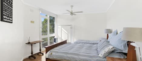 Un dormitorio con cama, mesita de noche, lámpara y ventilador de techo.